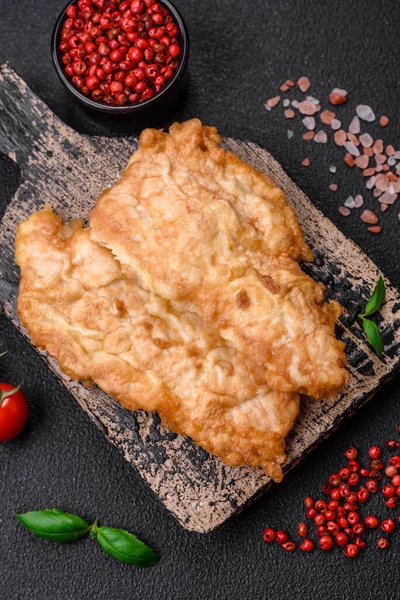 stock image Delicious fried chicken chop or pork meat fried breaded with salt, spices and herbs on a dark concrete background