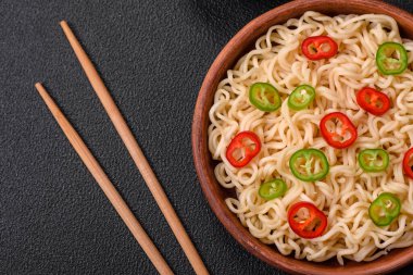 Lezzetli Asya mutfağı. İçinde pirinç, erişte, biber, mantar ve baharatlar var. Koyu beton arka planda.