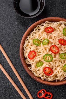 Lezzetli Asya mutfağı. İçinde pirinç, erişte, biber, mantar ve baharatlar var. Koyu beton arka planda.