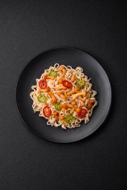 Lezzetli Asya mutfağı. İçinde pirinç, erişte, biber, mantar ve baharatlar var. Koyu beton arka planda.