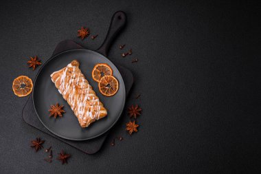 Lezzetli çıtır çıtır örülmüş çörek, içinde kuru üzüm, dışında beyaz krema, koyu beton arka planda.