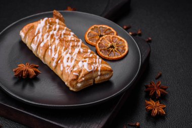 Lezzetli çıtır çıtır örülmüş çörek, içinde kuru üzüm, dışında beyaz krema, koyu beton arka planda.