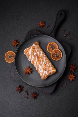 Lezzetli çıtır çıtır örülmüş çörek, içinde kuru üzüm, dışında beyaz krema, koyu beton arka planda.