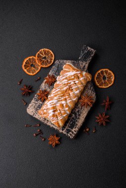 Lezzetli çıtır çıtır örülmüş çörek, içinde kuru üzüm, dışında beyaz krema, koyu beton arka planda.