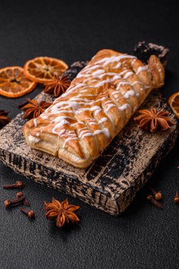 Lezzetli çıtır çıtır örülmüş çörek, içinde kuru üzüm, dışında beyaz krema, koyu beton arka planda.