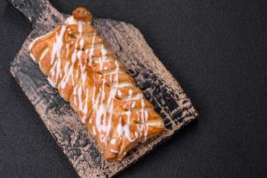 Lezzetli çıtır çıtır örülmüş çörek, içinde kuru üzüm, dışında beyaz krema, koyu beton arka planda.