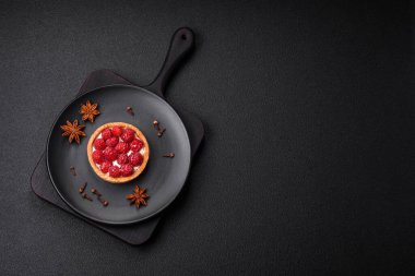 Olgun ahududu ve kremalı lezzetli, taze, yuvarlak turta. Koyu beton arka planda.