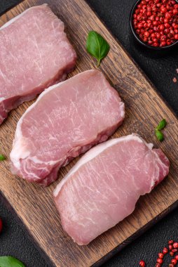 Tahta kesme tahtasına tuz, baharat ve otlu çiğ domuz eti.