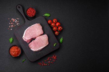 Tahta kesme tahtasına tuz, baharat ve otlu çiğ domuz eti.