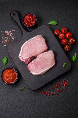 Tahta kesme tahtasına tuz, baharat ve otlu çiğ domuz eti.