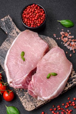 Tahta kesme tahtasına tuz, baharat ve otlu çiğ domuz eti.