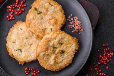 Lezzetli kızarmış balık pirzolası ya da koyu beton arka planda tuzlu, baharatlı ve otlu köfte.