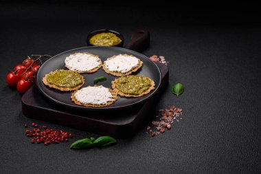 Çıtır cipsli yuvarlak atıştırmalıklar ya da krem peynirli krakerler ve seramik tabakta pesto.