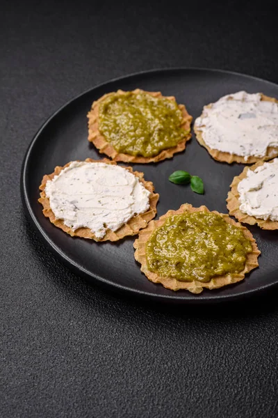 Çıtır cipsli yuvarlak atıştırmalıklar ya da krem peynirli krakerler ve seramik tabakta pesto.