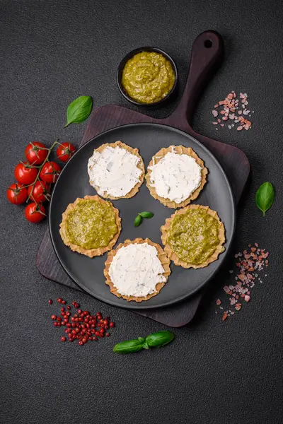 Çıtır cipsli yuvarlak atıştırmalıklar ya da krem peynirli krakerler ve seramik tabakta pesto.