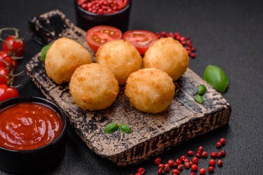 Lezzetli yuvarlak mozzarella topları ve parmesan peyniri, tuzlu ve ekşi baharatlı koyu beton arka planda. Fast food, sağlıksız yemek