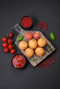 Lezzetli yuvarlak mozzarella topları ve parmesan peyniri, tuzlu ve ekşi baharatlı koyu beton arka planda. Fast food, sağlıksız yemek