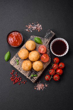 Lezzetli yuvarlak mozzarella topları ve parmesan peyniri, tuzlu ve ekşi baharatlı koyu beton arka planda. Fast food, sağlıksız yemek