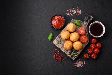 Lezzetli yuvarlak mozzarella topları ve parmesan peyniri, tuzlu ve ekşi baharatlı koyu beton arka planda. Fast food, sağlıksız yemek