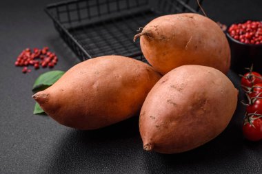 Koyu arkaplanda domates ve baharatlı taze, büyük, pembe patates şişeleri. Sağlıklı bir vejetaryen yemeği pişirmek.