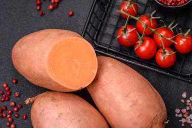 Koyu arkaplanda domates ve baharatlı taze, büyük, pembe patates şişeleri. Sağlıklı bir vejetaryen yemeği pişirmek.