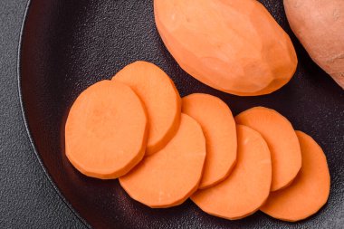 Koyu arkaplanda domates ve baharatlı taze, büyük, pembe patates şişeleri. Sağlıklı bir vejetaryen yemeği pişirmek.