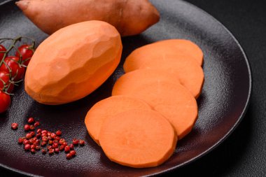 Koyu arkaplanda domates ve baharatlı taze, büyük, pembe patates şişeleri. Sağlıklı bir vejetaryen yemeği pişirmek.