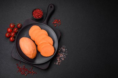 Koyu arkaplanda domates ve baharatlı taze, büyük, pembe patates şişeleri. Sağlıklı bir vejetaryen yemeği pişirmek.