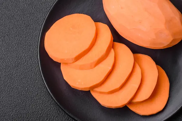 Koyu arkaplanda domates ve baharatlı taze, büyük, pembe patates şişeleri. Sağlıklı bir vejetaryen yemeği pişirmek.