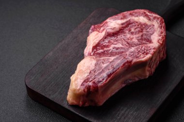 Taze, sulu, çiğ biftek, tuzlu ve baharatlı, koyu beton bir arka planda.