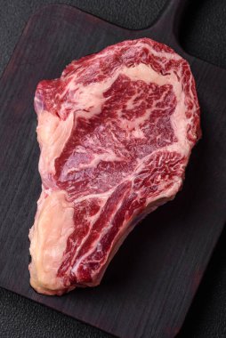 Taze, sulu, çiğ biftek, tuzlu ve baharatlı, koyu beton bir arka planda.