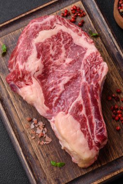 Taze, sulu, çiğ biftek, tuzlu ve baharatlı, koyu beton bir arka planda.