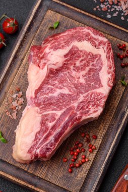 Taze, sulu, çiğ biftek, tuzlu ve baharatlı, koyu beton bir arka planda.