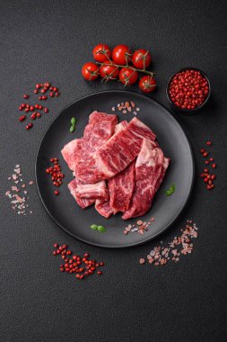 Koyu beton zeminde tuzlu ve baharatlı taze çiğ et dilimleri.