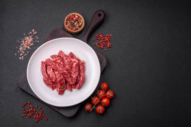 Koyu beton zeminde tuzlu ve baharatlı taze çiğ et dilimleri.
