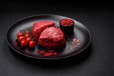 Koyu beton arka planda tuz ve baharatlı taze çiğ et madalyonları.