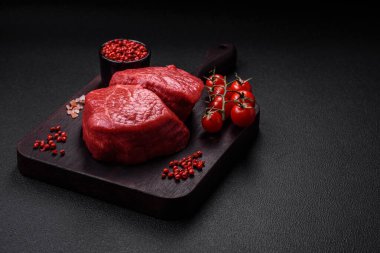 Koyu beton arka planda tuz ve baharatlı taze çiğ et madalyonları.