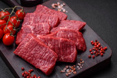 Koyu beton zeminde tuzlu ve baharatlı taze çiğ et dilimleri.