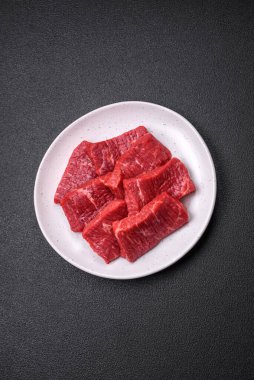 Koyu beton zeminde tuzlu ve baharatlı taze çiğ et dilimleri.