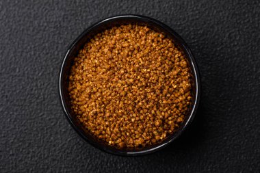 Kahverengi Svan tuzu kristalleri. Siyah bir kasede koyu beton bir arka planda baharatlar var.