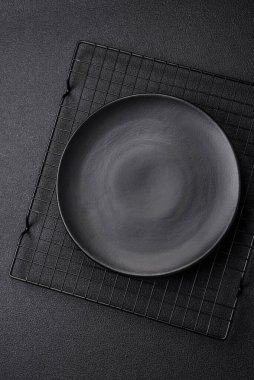 Empty ceramic round plate on dark textured concrete background. Cutlery, preparation for dinner