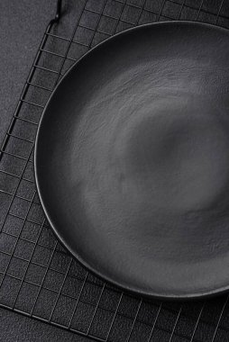 Empty ceramic round plate on dark textured concrete background. Cutlery, preparation for dinner