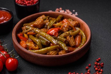 Sebze, mısır, havuç, biber, teriyaki soslu soğan karışımı koyu beton arka planda seramik bir tabakta.