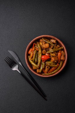 Sebze, mısır, havuç, biber, teriyaki soslu soğan karışımı koyu beton arka planda seramik bir tabakta.
