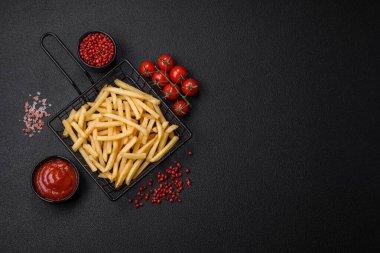 Koyu beton zeminde tuzlu ve baharatlı taze kızarmış patates kızartması.