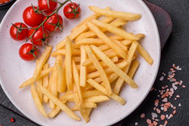 Koyu beton zeminde tuzlu ve baharatlı taze kızarmış patates kızartması.