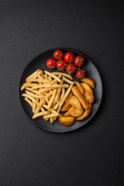 Koyu beton zeminde tuzlu ve baharatlı taze kızarmış patates kızartması.