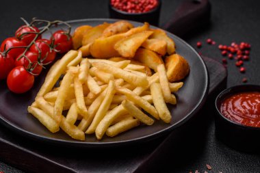 Koyu beton zeminde tuzlu ve baharatlı taze kızarmış patates kızartması.