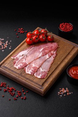 Lezzetli füme jamon dilimleri ya da koyu beton arka planda tuzlu, baharatlı ve otlu jambon.