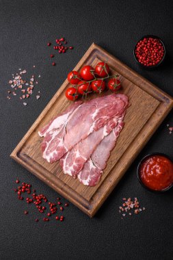 Lezzetli füme jamon dilimleri ya da koyu beton arka planda tuzlu, baharatlı ve otlu jambon.